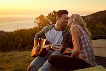 I wrote this song for you. Shot of a young man playing guitar for his girlfriend on a roadtrip.