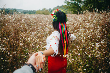 Follow woman in traditional Ukrainian costume embroidery in field