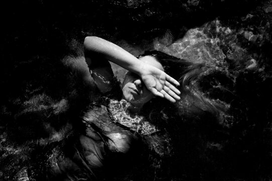 girl lying on the water covering part of her face with her hand