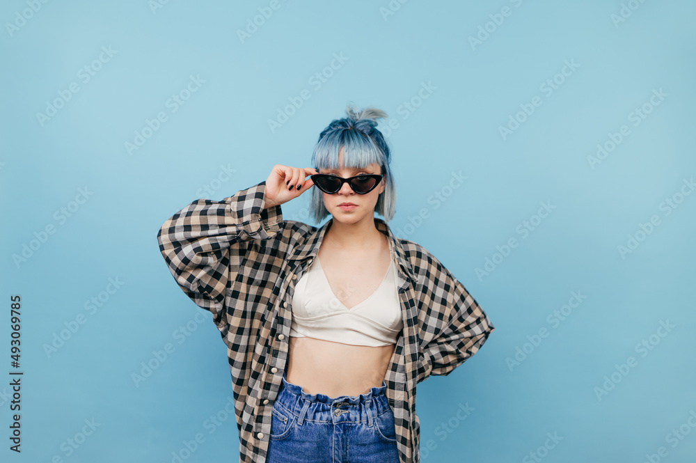 Wall mural portrait of a young teen girl with a bright appearance on a blue background posing at camera with a 