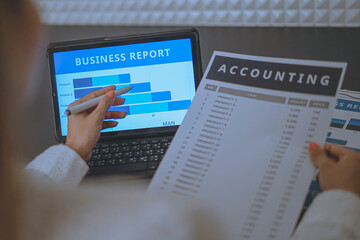 Business woman reviewing data in financial charts and graphs on wooden desk in office and business working, tax, accounting, statistics and analytic research concept