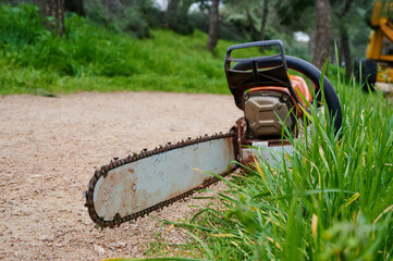 Gasoline power saw placed on ground during a break from loggers cutting tree branches.