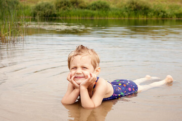 Little girl lying on  stomach in   water in   river