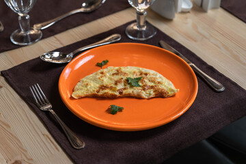 A photo of an omelette is laid out on an orange plate.