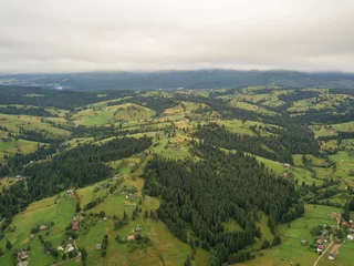 Foto op Canvas Green slopes of Ukrainian Carpathian mountains in summer. Cloudy morning, low clouds. Aerial drone view. © Sergey