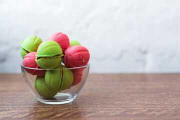 Multicolored cookies in the form of Nuts with filled cream in a glass transparent vase on table on a light background
