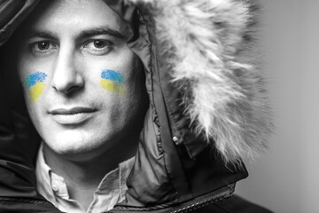 Ritratto di un uomo con la bandiera dell'Ucraina disegnata sul viso e un cappello con la pelliccia