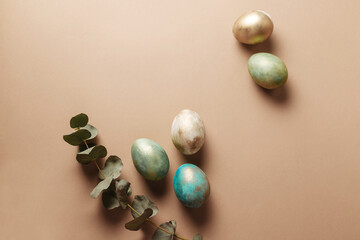 Creatively colored easter eggs on a brown background with eucalyptus. Stylish banner in the style of minimalism with eggs