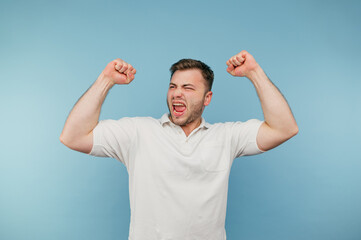 Portrait of a joyful man in a white T-shirt on a blue background with a happy face emotionally happy.