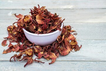 Dry Roselle Fruit or Hibiscus Sabdariffa in a Bowl Isolated on White Wooden Background