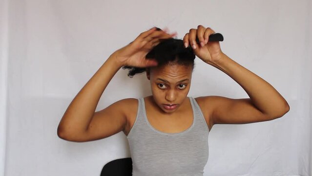 Young African Woman combing her 4C natural hair on white background
