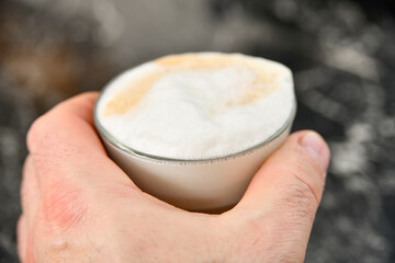 A man holds a cup of espresso coffee in his hand.