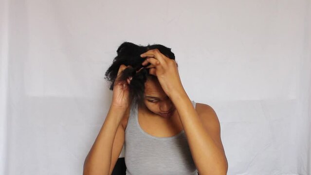 Young African Woman plating her 4C natural hair on a white background