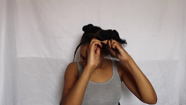 Young African Woman plating the front of her 4C natural hair on a white background