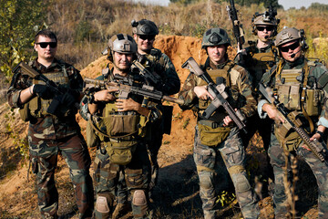 Fototapeta premium military men, group of soldiers posing at camera carrying rifle guns, weapons. The concept of military operations, special operations. team of soldiers looking at camera, friendly group of soldiers