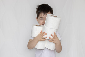 cute little boy is holding toilet paper rolls in arms, or is looking through the hole. stack of wc...