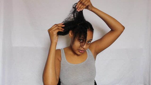 Young African Woman separating her 4C natural hair on a white background