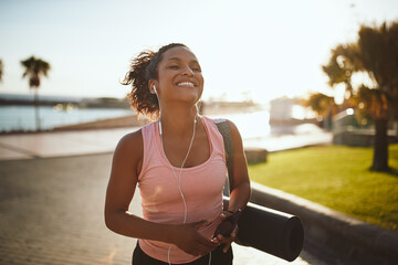 Laughing young woman listening to music while walking to yoga