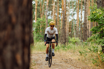 Male cyclist in sportswear rides on a forest trail on a bicycle with a serious face on a background...