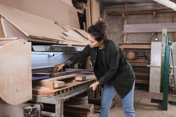 Young carpenter polishing wooden board in workshop.