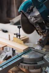 Close up view of miter saw and wooden board in workshop.