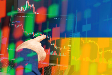 Ukraine downtrend of the economy in a world crisis. Man hand shows on the decreasing candle stick graph chart in the stock market with the flag on the background, March 2022, San Francisco, USA