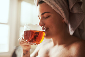 How tea lovers start their days. Shot of a young woman having tea while going through her morning beauty routine at home.