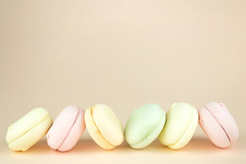 Colorful marshmallows looks like french macarons on pastel beige background, close up.