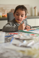 young caucasian boy doing painting at home with pleasure