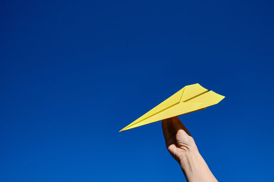 Paper yellow plane in the hands against the blue sky. Taking flight! Travel concept