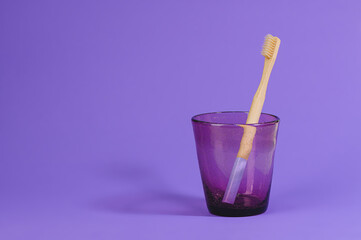 wooden toothbrush in a glass on a purple background