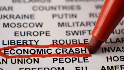 Obraz premium Closeup shot of ECONOMIC CRASH written on white paper with a red circle. Military activities. Sanctions. Crisis. Russian invasion of Ukraine concept. 