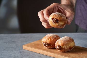 man's hand serving a Berliner stuffed with dulce de leche