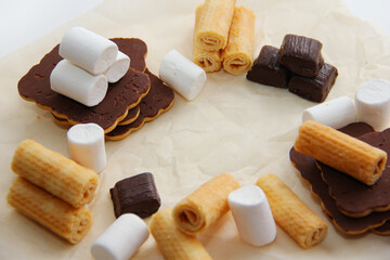 sweets, chocolates, cookies, waffles, marshmallows on parchment paper
