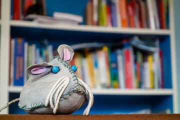Ratte vor verschwommenem Bücherregal. Buch liebende graue Maus mit blauen Augen und rosa Ohren....