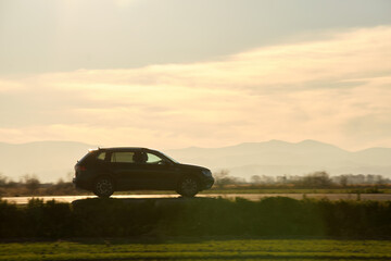 Fototapeta premium Car driving fast on intercity road at sunset. Highway traffic in evening