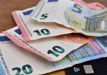 euro bills and a plastic card on a wooden table