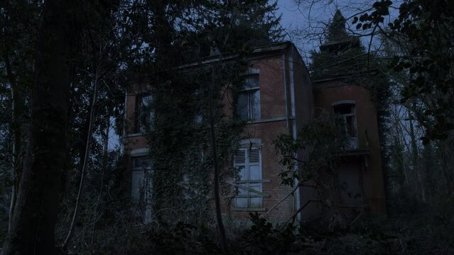 Abandoned mansion ruin in a forest nighttime tilt down from sky
