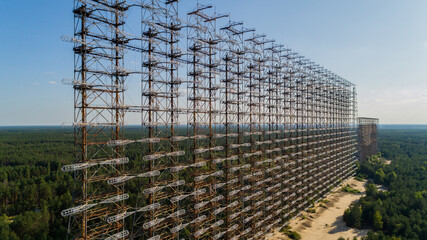 Fototapeta premium Close up aerial view of the DUGA radar station near the city of Chernobyl-2 among the forest in sunny day. Drone shot Chernobyl exclusion zone in summer. Radiation
