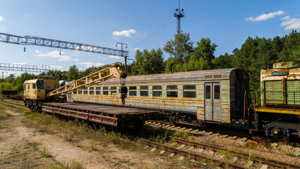 Obraz premium Aerial view of a dump of abandoned rusty trains and crane among the forest in city Pripyat near Chernobyl nuclear power plant. Drone shot Exclusion Zone in summer on a sunny day. Radiation