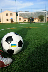 pallone da calcio  con. sopra la bandiera con i  colori dell'Ucraina mentre si calcia un rigore
