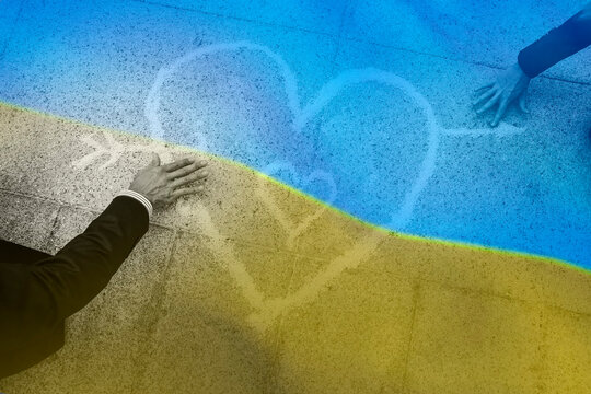 cuore disegnato nel marciapiede con i colori dell'Ucraina e due mani che lo accarezzano