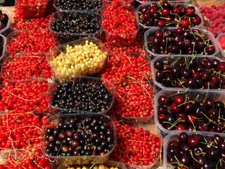 Fresh jostaberries, redcurrants, white currants and cherries on a farmers market stall in London, England, UK.    