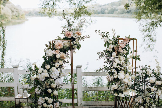 Wedding arch with fresh flowers of roses by the lake in the park