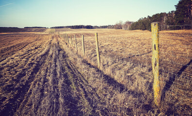 Agricultural field with wire fence, color toning applied.