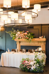 Coziness and style. Modern event design. Table setting at wedding reception. Floral compositions with beautiful flowers and greenery, candles, laying and plates on decorated table.