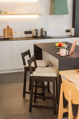 Laptop in the kitchen at home. Computer and a cup of tea. Work from home remotely. Home comfort, hobby