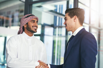 Business built on a mutual purpose. Shot of a young muslim businessman shaking hands with an associate in a modern office.