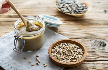 Homemade sunflower seed spread with seeds on a wooden background