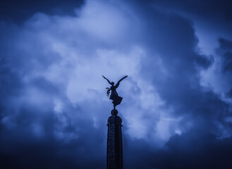 Fototapeta na wymiar A statue of an angel standing on top of an obelisk